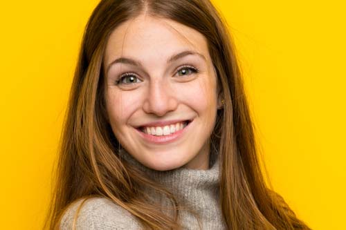 cosmetic dentistry woman smiling yellow background