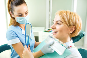 woman during dental veneer services in tx looking at her dental veneers tx in the the mirror