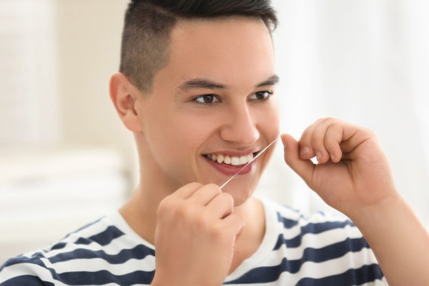 benefits of flossing daily (3) person flossing to get the Benefits of Flossing Daily