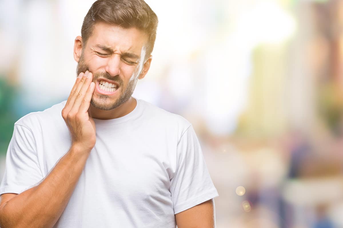 man walking in the city in pain from a tooth cavity